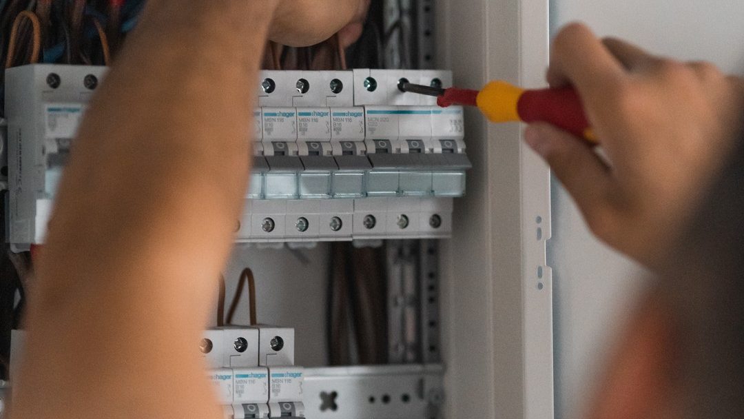 Elektriker von Das Elektroteam zieht Sicherungsautomat in einer Unterverteilung fest